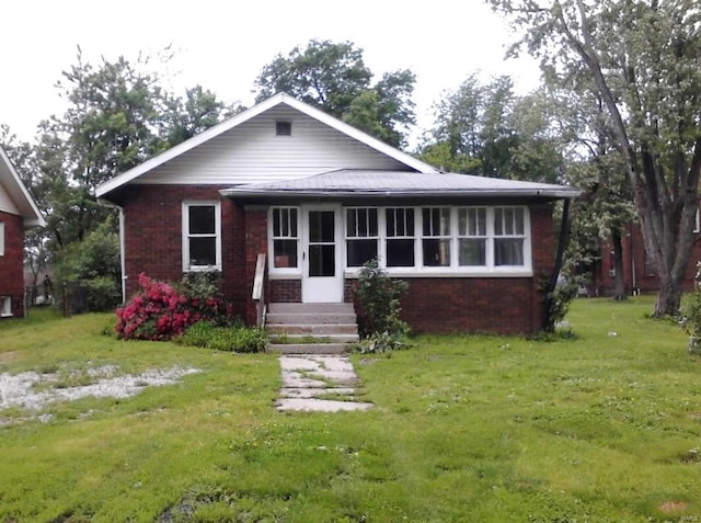 view of front of property featuring a front lawn, a sunroom, and brick siding