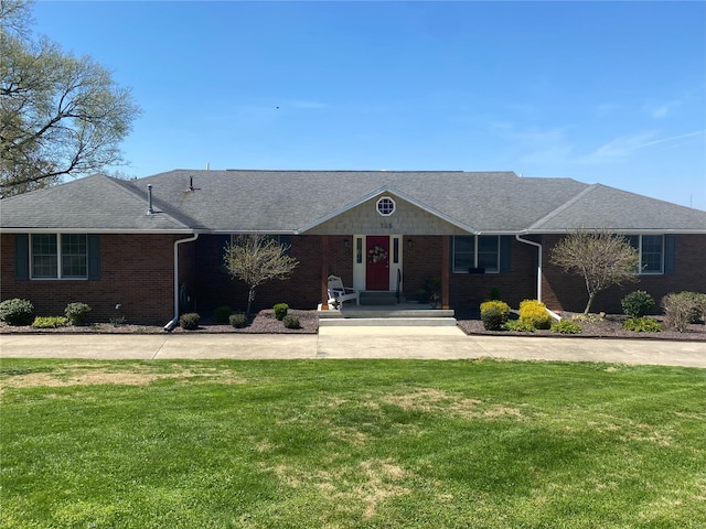 ranch-style home featuring a front yard, brick siding, and roof with shingles