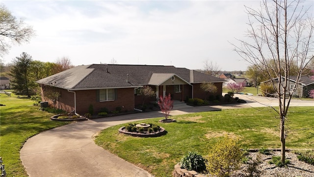 ranch-style home with a front yard, brick siding, a shingled roof, and curved driveway