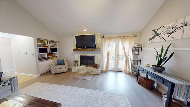 living area featuring baseboards, high vaulted ceiling, wood finished floors, and a fireplace