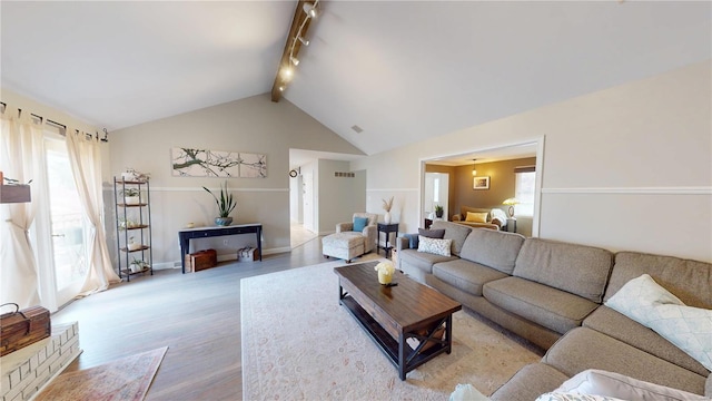 living area featuring track lighting, light wood finished floors, lofted ceiling with beams, and baseboards