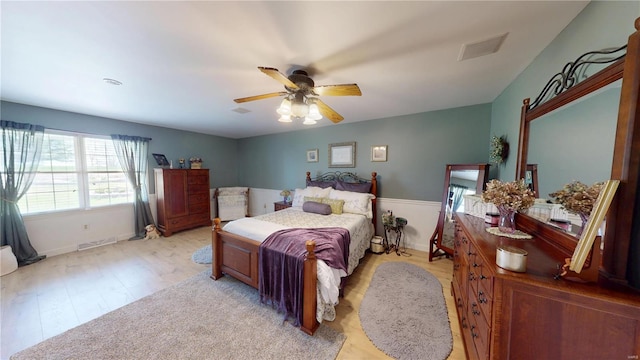 bedroom featuring visible vents, light wood-style flooring, a ceiling fan, and baseboards