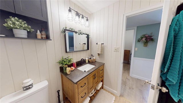 half bath with toilet, vanity, and wood finished floors