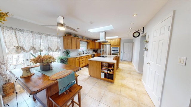kitchen featuring island range hood, light countertops, a skylight, stainless steel appliances, and a sink