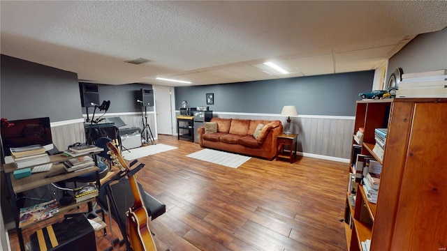 living room featuring visible vents, a wainscoted wall, wood finished floors, and a textured ceiling