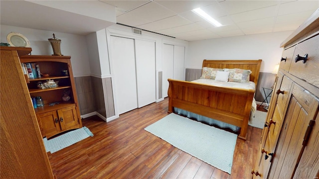 bedroom with visible vents, baseboards, two closets, and wood finished floors