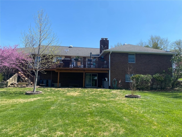 rear view of property featuring a yard, brick siding, a deck, and a chimney