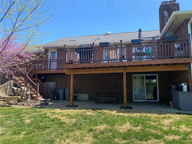 back of property featuring a deck, a yard, a patio, stairs, and brick siding