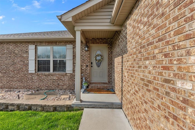 property entrance with roof with shingles and brick siding