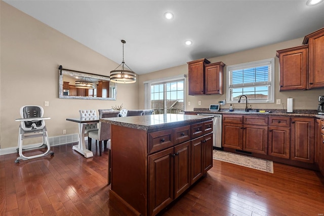kitchen with vaulted ceiling, dark countertops, dark wood finished floors, stainless steel dishwasher, and a sink