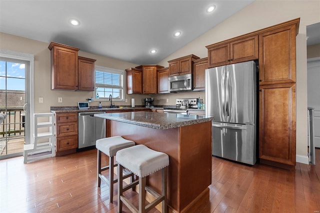 kitchen with a breakfast bar area, wood-type flooring, a center island, and stainless steel appliances