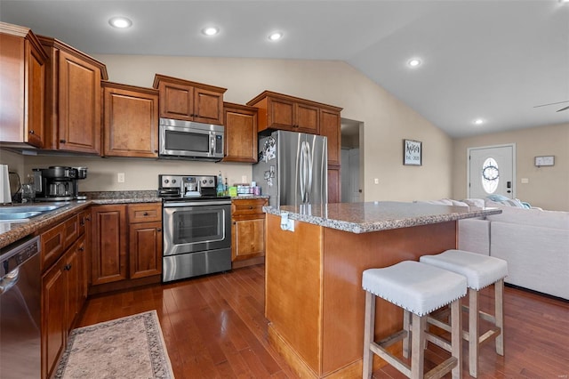kitchen featuring a kitchen breakfast bar, dark wood-type flooring, lofted ceiling, stainless steel appliances, and open floor plan