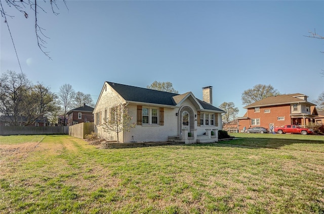 view of front of property featuring a front yard, fence, and a chimney
