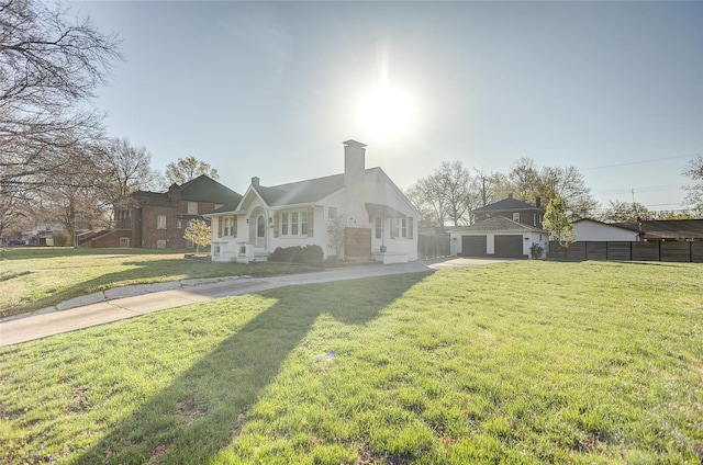 view of front of home with a chimney, driveway, a front yard, an outbuilding, and fence