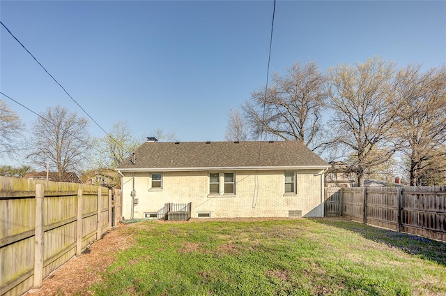 back of house with a shingled roof, a yard, a fenced backyard, and a chimney
