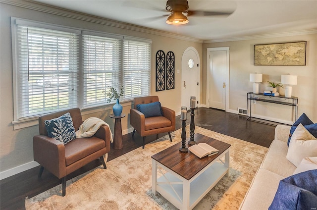 living room featuring ceiling fan, baseboards, ornamental molding, and wood finished floors
