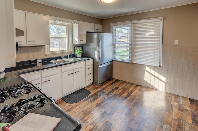 kitchen with dark wood-style floors, white cabinetry, freestanding refrigerator, dark countertops, and a sink