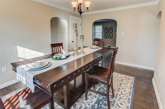 dining room with ornamental molding, baseboards, arched walkways, and wood finished floors
