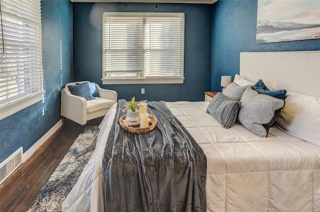 bedroom featuring visible vents, baseboards, and wood finished floors