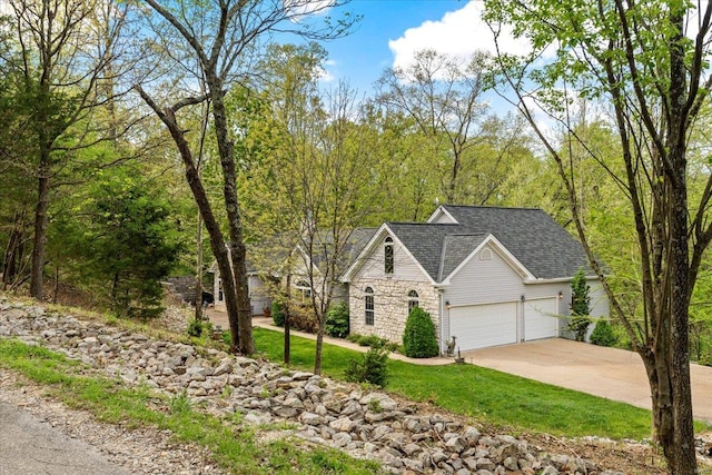 traditional home with a front lawn, a shingled roof, driveway, stone siding, and an attached garage