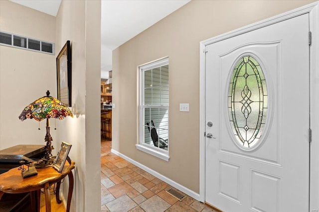foyer entrance featuring stone finish flooring, visible vents, and baseboards