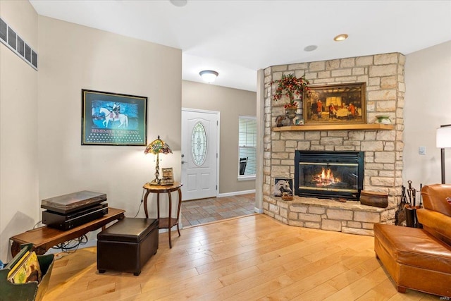 living room with light wood-type flooring, visible vents, and a fireplace