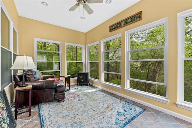 sunroom featuring recessed lighting, a wood stove, and baseboards