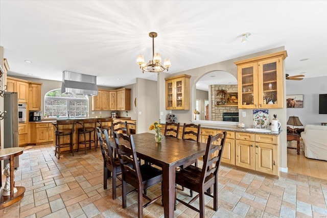 dining room with stone tile floors, recessed lighting, a notable chandelier, and arched walkways