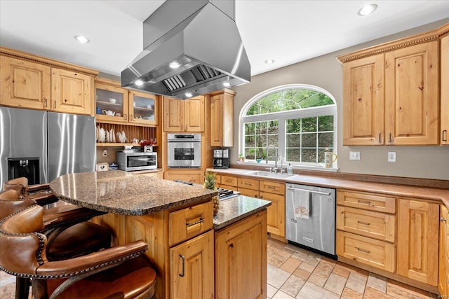 kitchen featuring extractor fan, appliances with stainless steel finishes, a kitchen island, a sink, and a kitchen breakfast bar