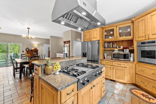 kitchen with exhaust hood, stainless steel appliances, stone tile floors, a center island, and a notable chandelier