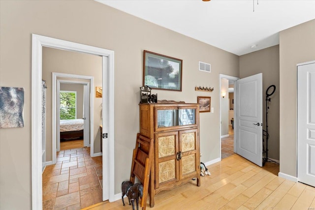 hall featuring baseboards and visible vents