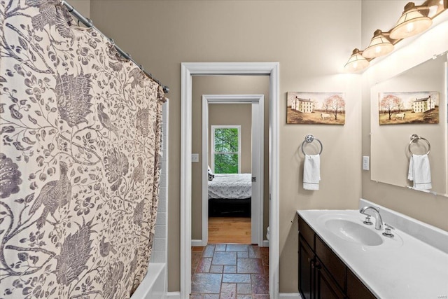 bathroom featuring vanity, stone tile flooring, and baseboards