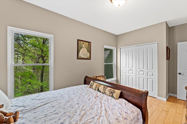 bedroom with a closet, light wood-style flooring, and baseboards