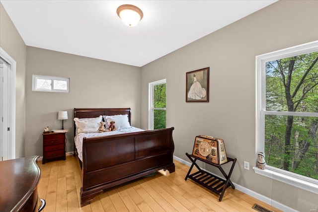 bedroom with baseboards, light wood-style floors, and multiple windows