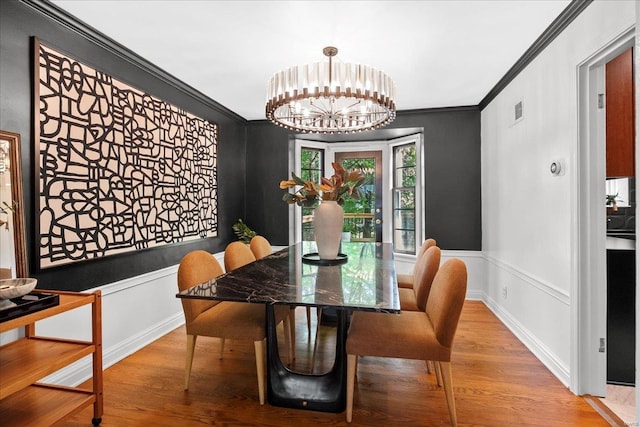 dining space with visible vents, ornamental molding, wood finished floors, and a chandelier