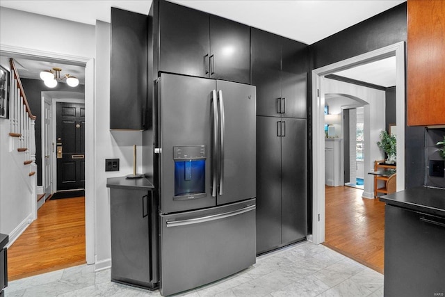 kitchen with stainless steel fridge, arched walkways, dark cabinetry, and marble finish floor