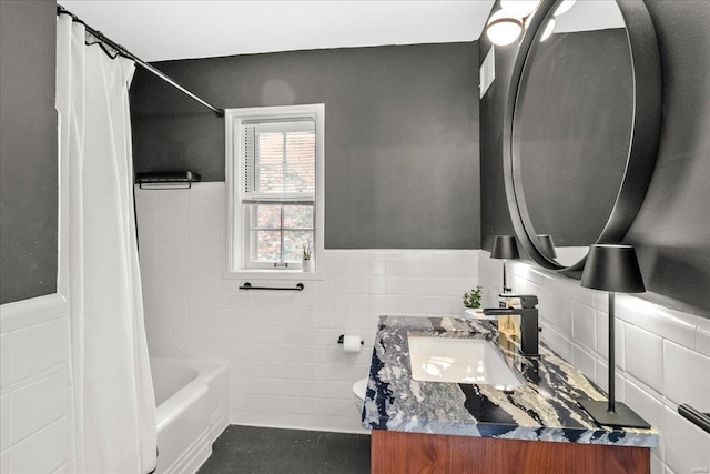 bathroom featuring vanity, tile walls, wainscoting, and shower / bathtub combination with curtain