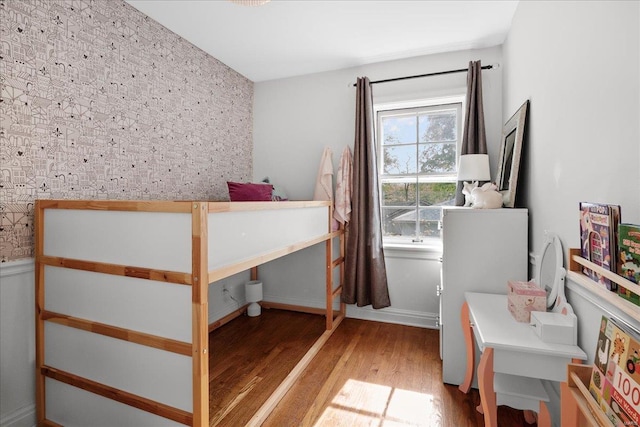 bedroom with wallpapered walls and wood finished floors