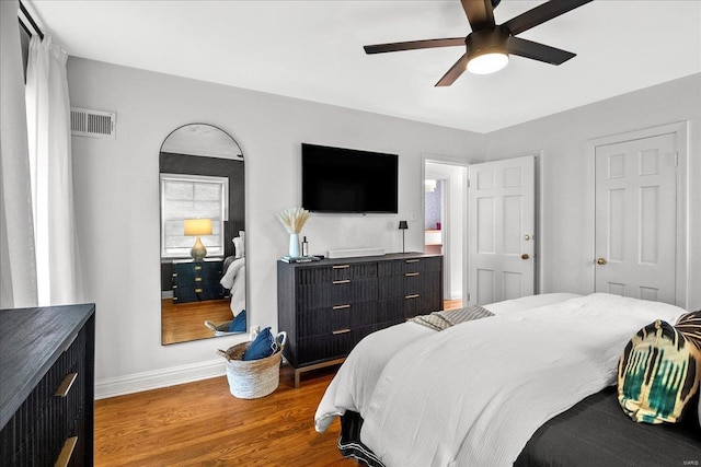 bedroom featuring baseboards, ceiling fan, wood finished floors, and visible vents