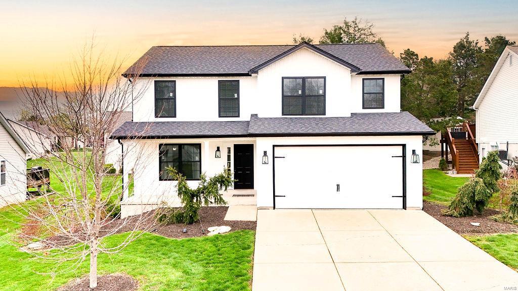modern farmhouse featuring concrete driveway, roof with shingles, stairway, and stucco siding