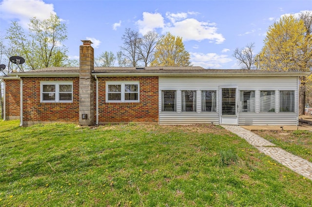 back of property featuring a yard, brick siding, and a chimney