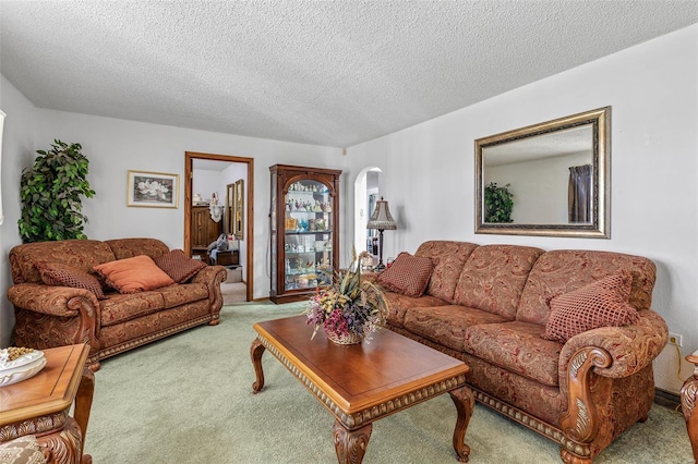 living area featuring arched walkways, carpet, and a textured ceiling
