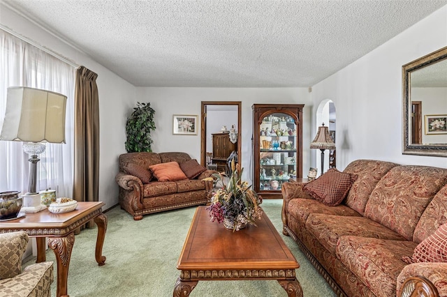 living room with arched walkways, a textured ceiling, and carpet floors