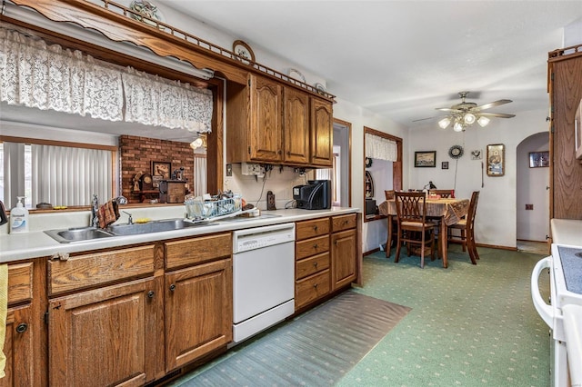 kitchen with white dishwasher, a sink, light countertops, carpet, and brown cabinets