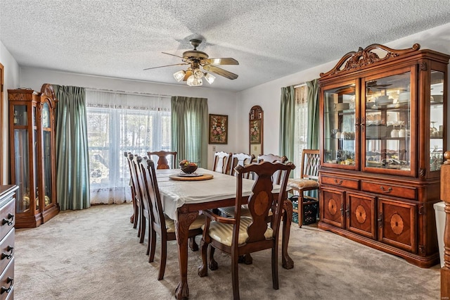 dining room featuring ceiling fan, light carpet, and a textured ceiling