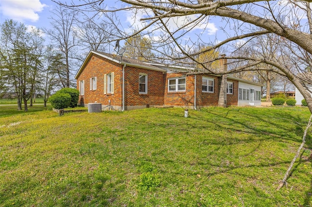 exterior space with brick siding, central AC, and a yard