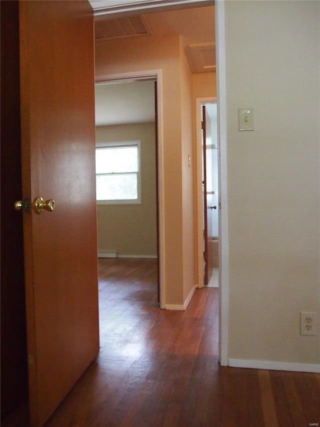 hallway featuring baseboards, wood finished floors, and visible vents
