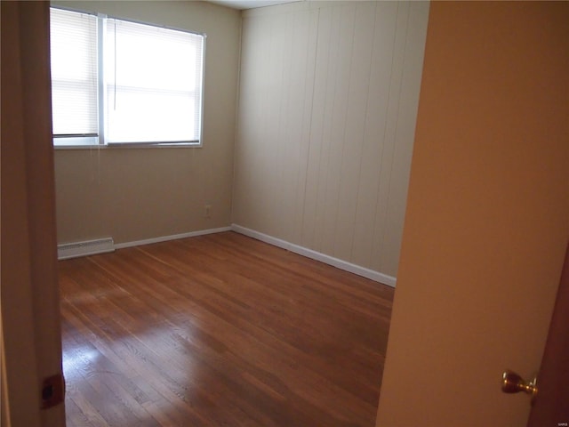unfurnished room featuring baseboards, wood finished floors, and visible vents