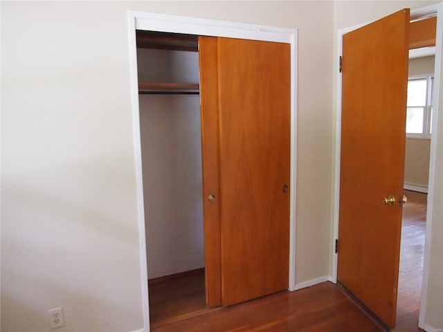 unfurnished bedroom featuring baseboards, a baseboard heating unit, wood finished floors, and a closet