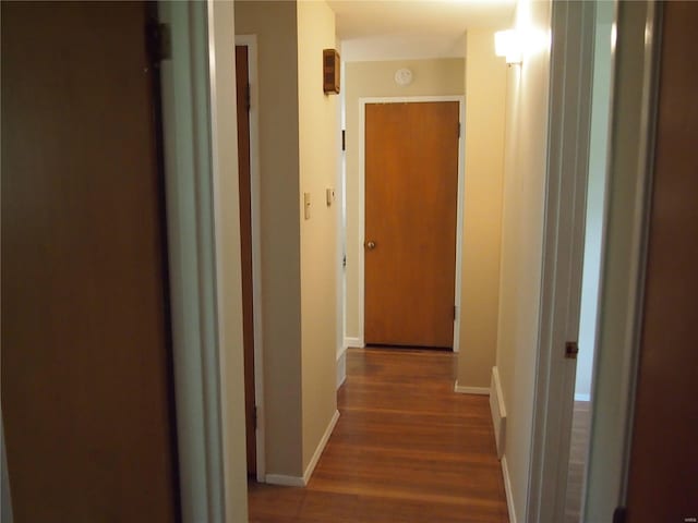 hallway featuring baseboards and wood finished floors